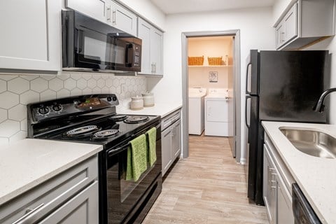 a kitchen with white cabinets and black appliances and a black refrigerator